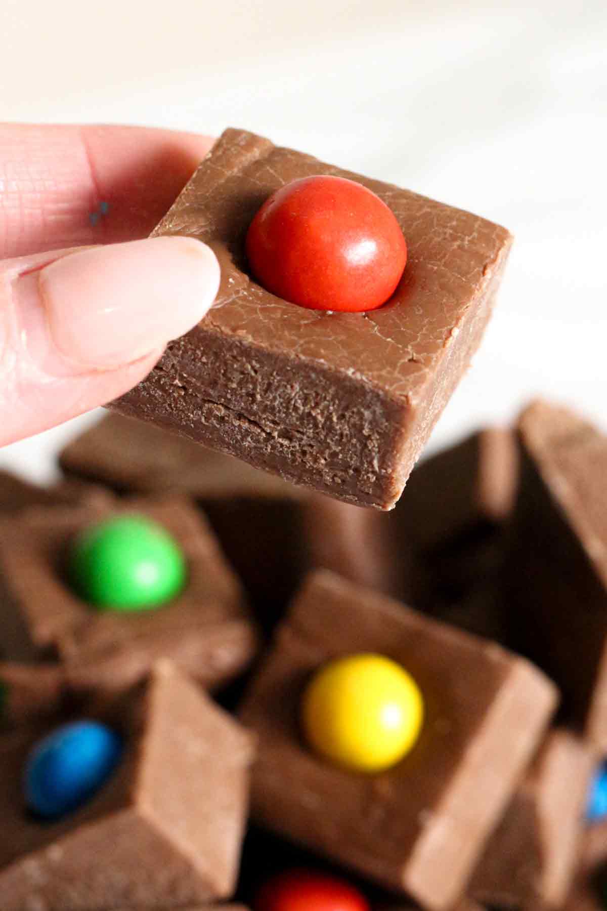 hand holding up a piece of chocolate 3-ingredient M&M fudge