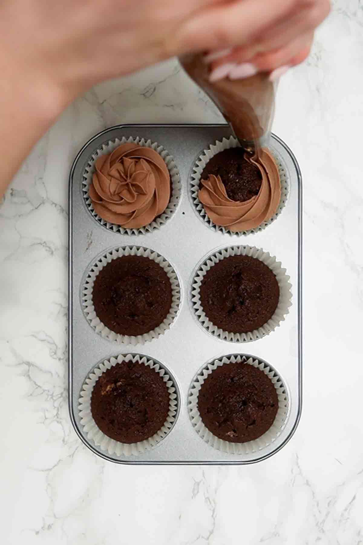 piping dairy milk buttercream onto cupcakes