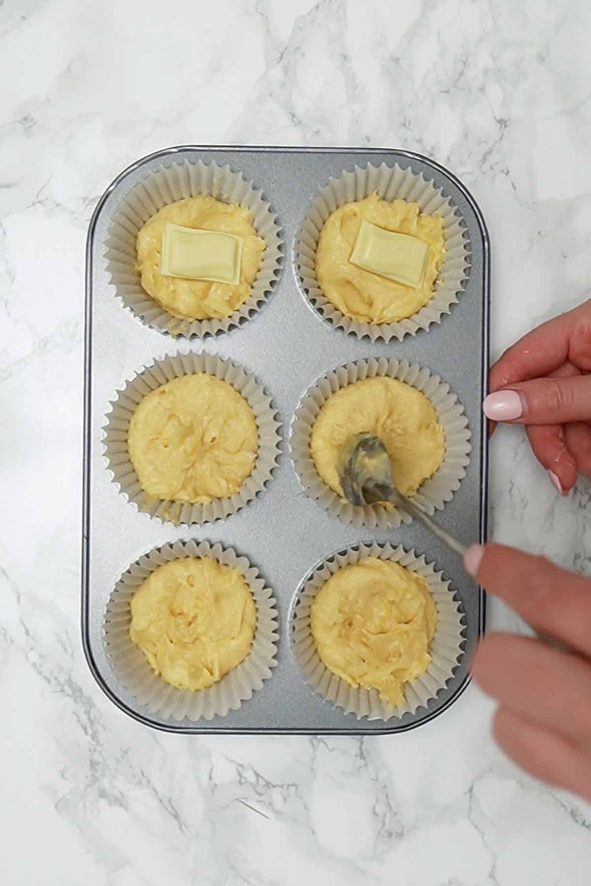 stuffing piece of milky bar chocolate into cupcake batter