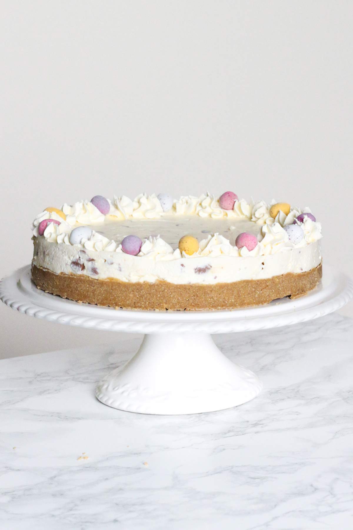whole mini egg cheesecake on a white cake stand