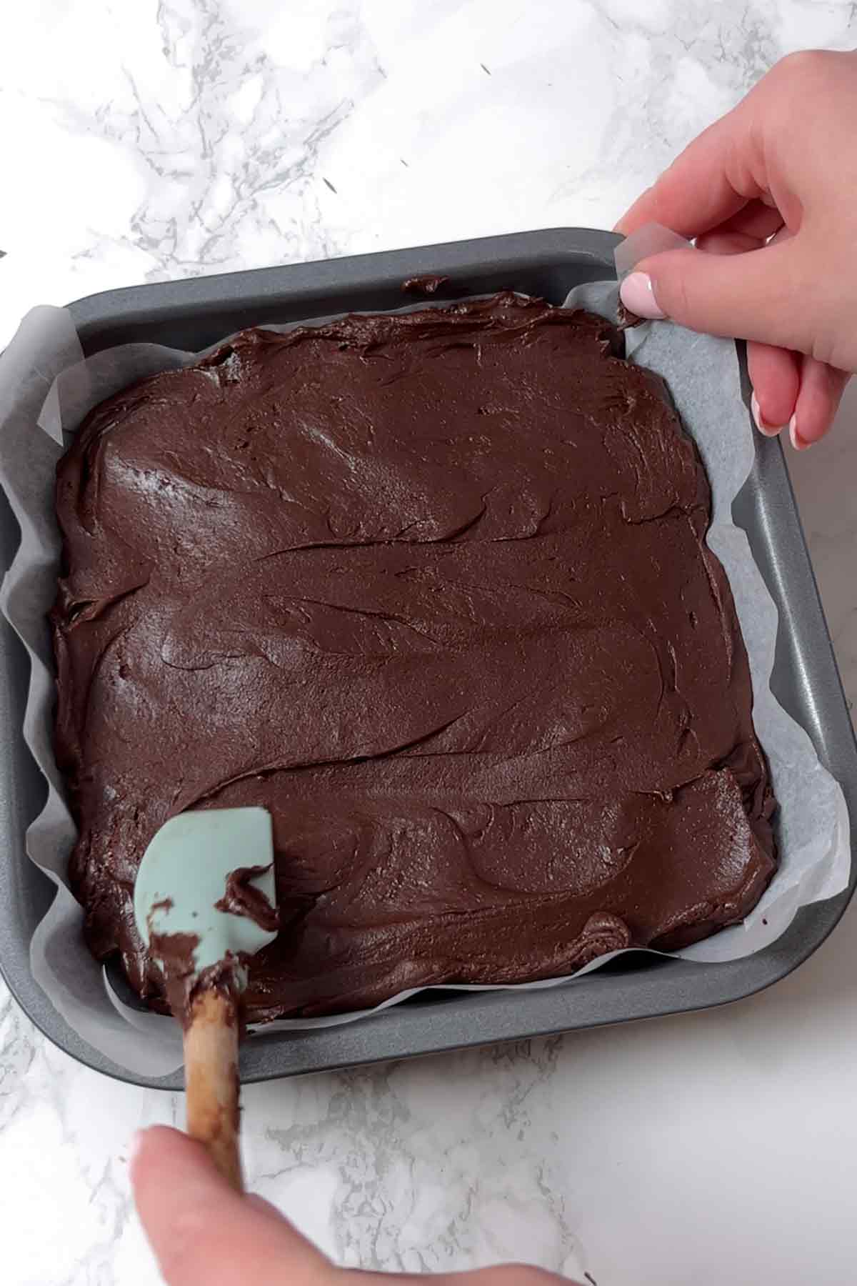 spreading brownie mix into tin