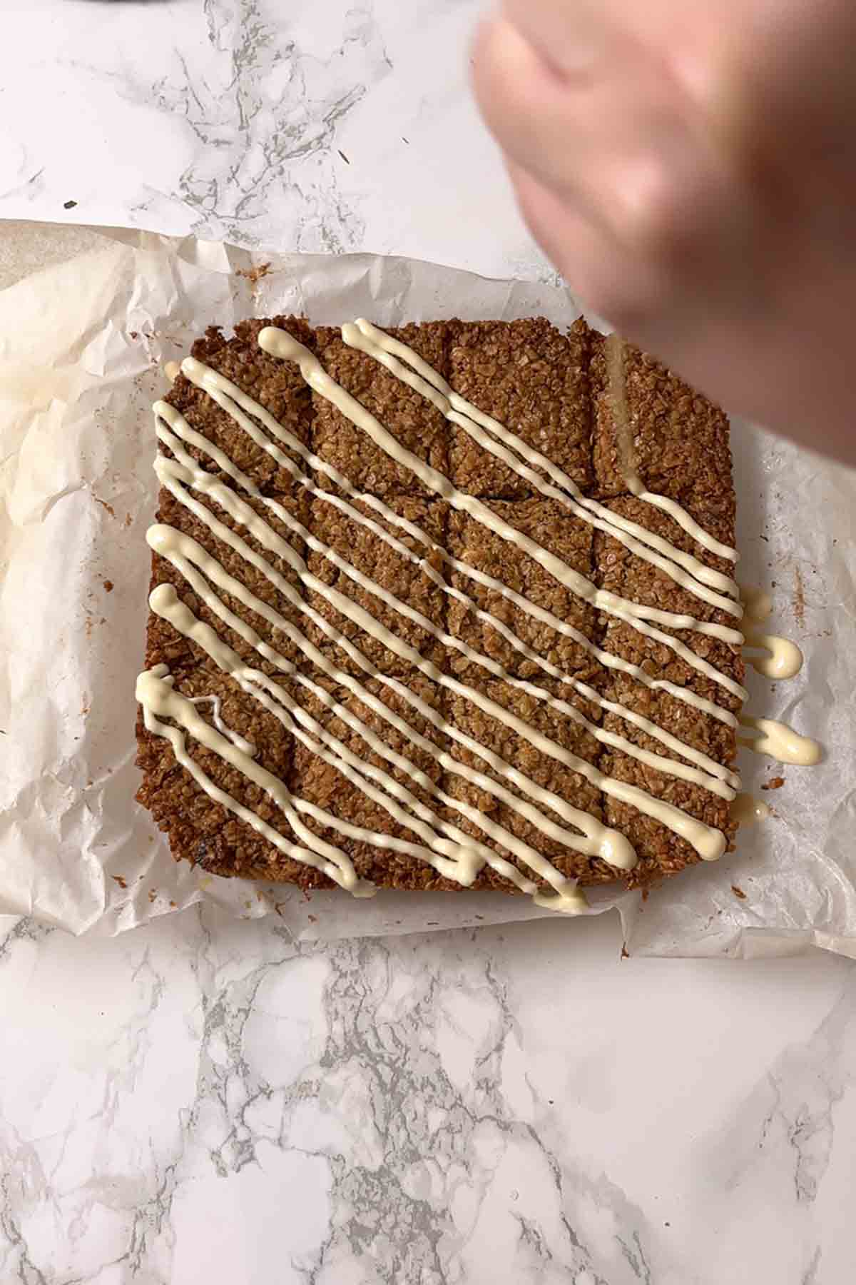 drizzling melted chocolate on top of flapjack