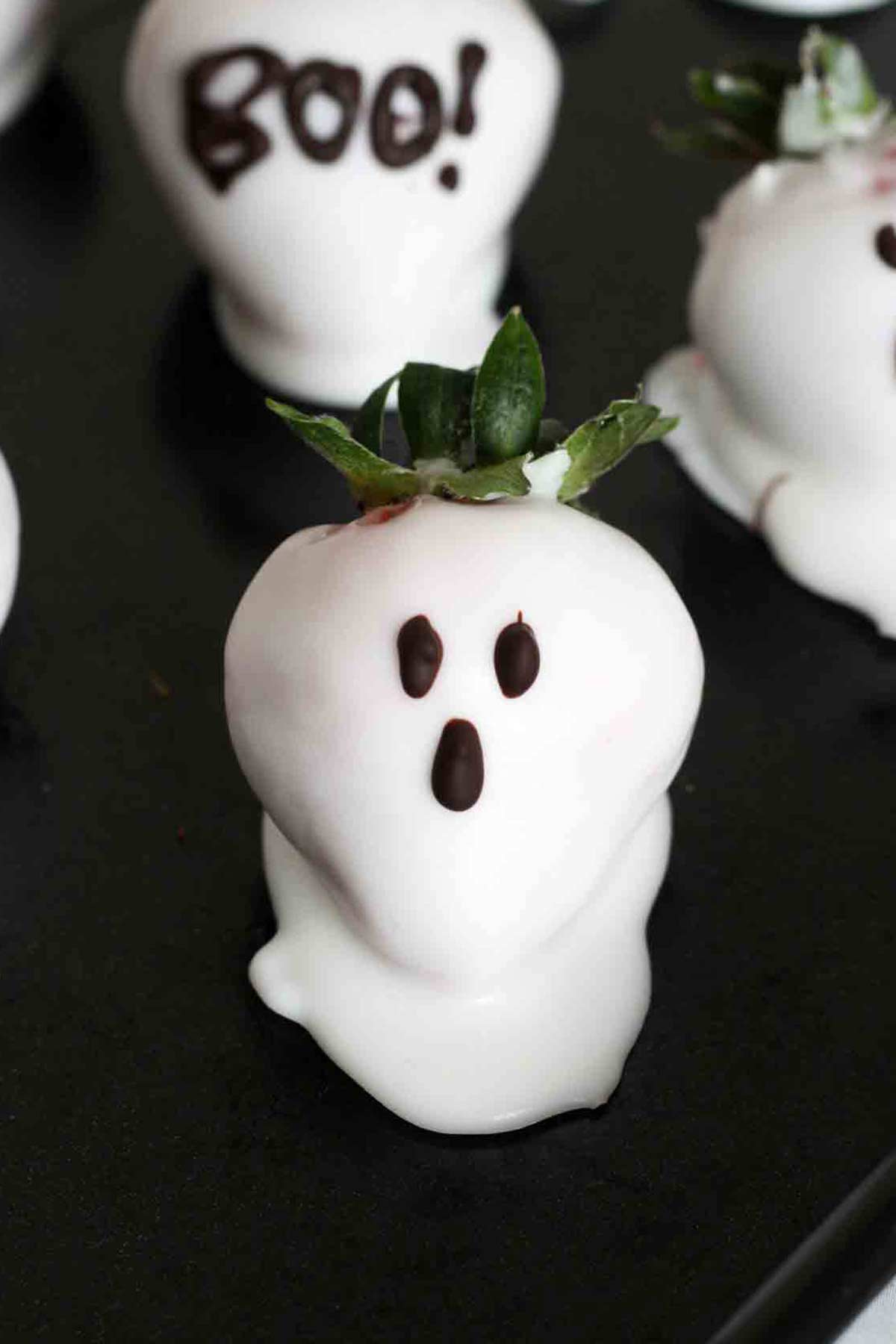 a tray full of halloween chocolate covered strawberry ghosts