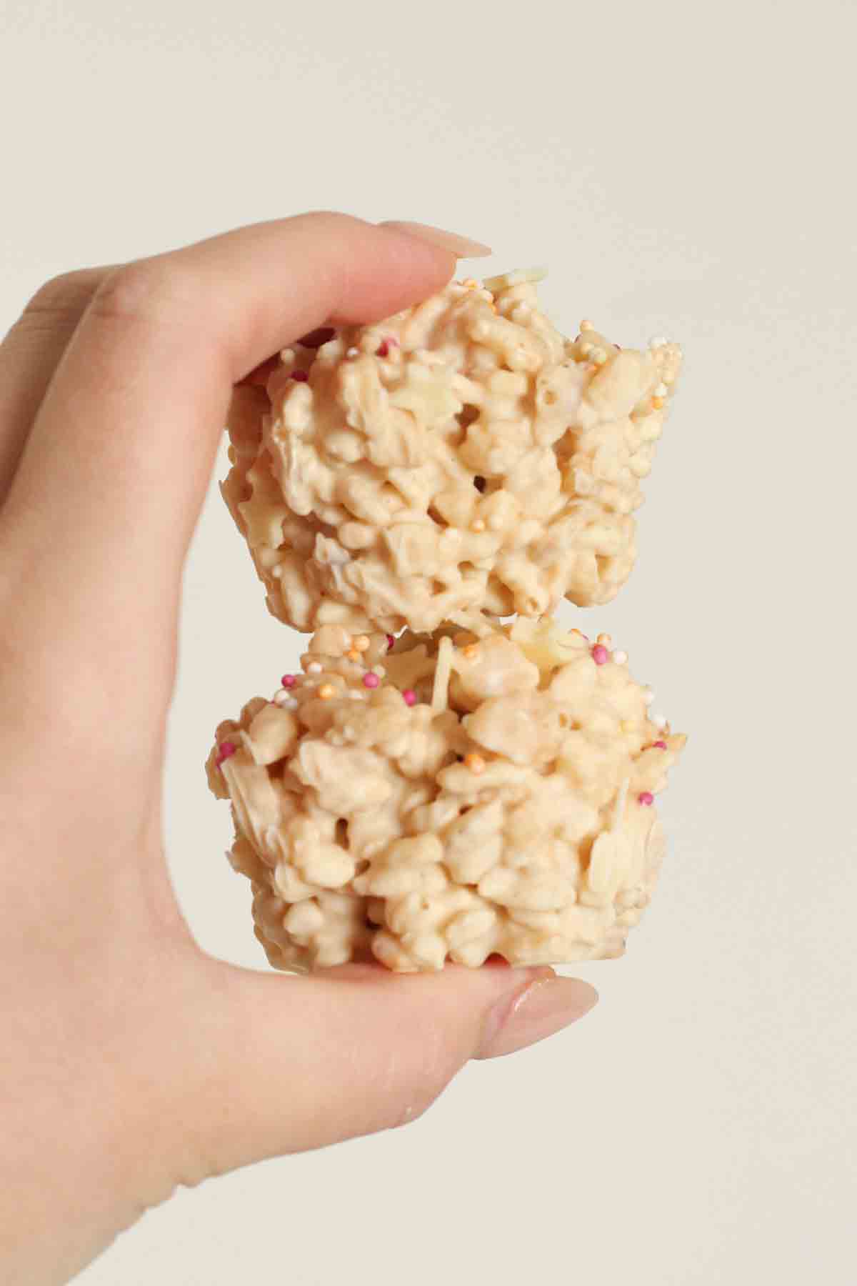 hand holding two white rice krispie cakes