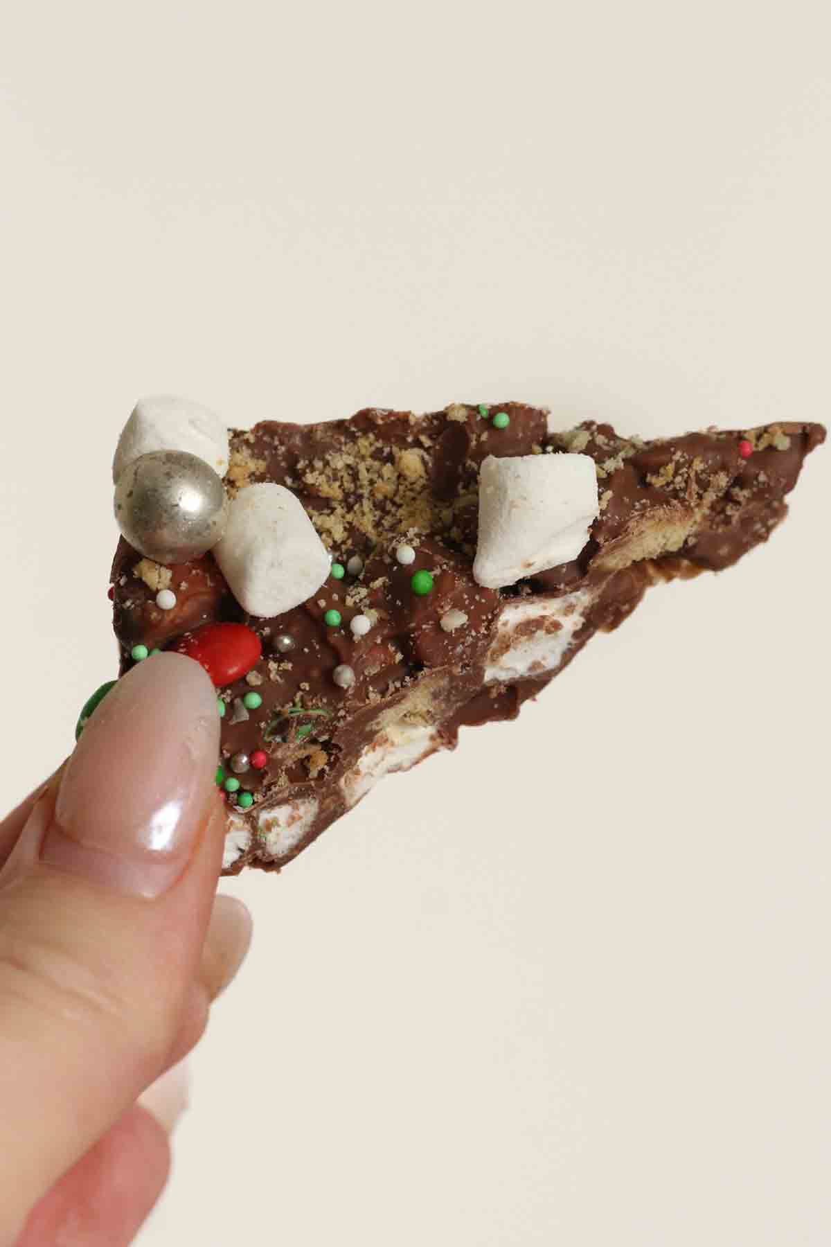 hand holding up a piece of christmas marshmallow smores bark
