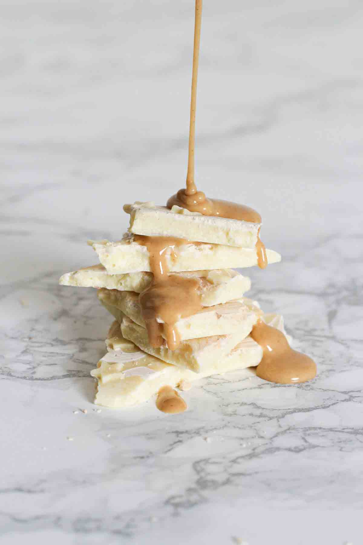 stack of peanut butter and white chocolate bark with peanut butter being drizzled on top