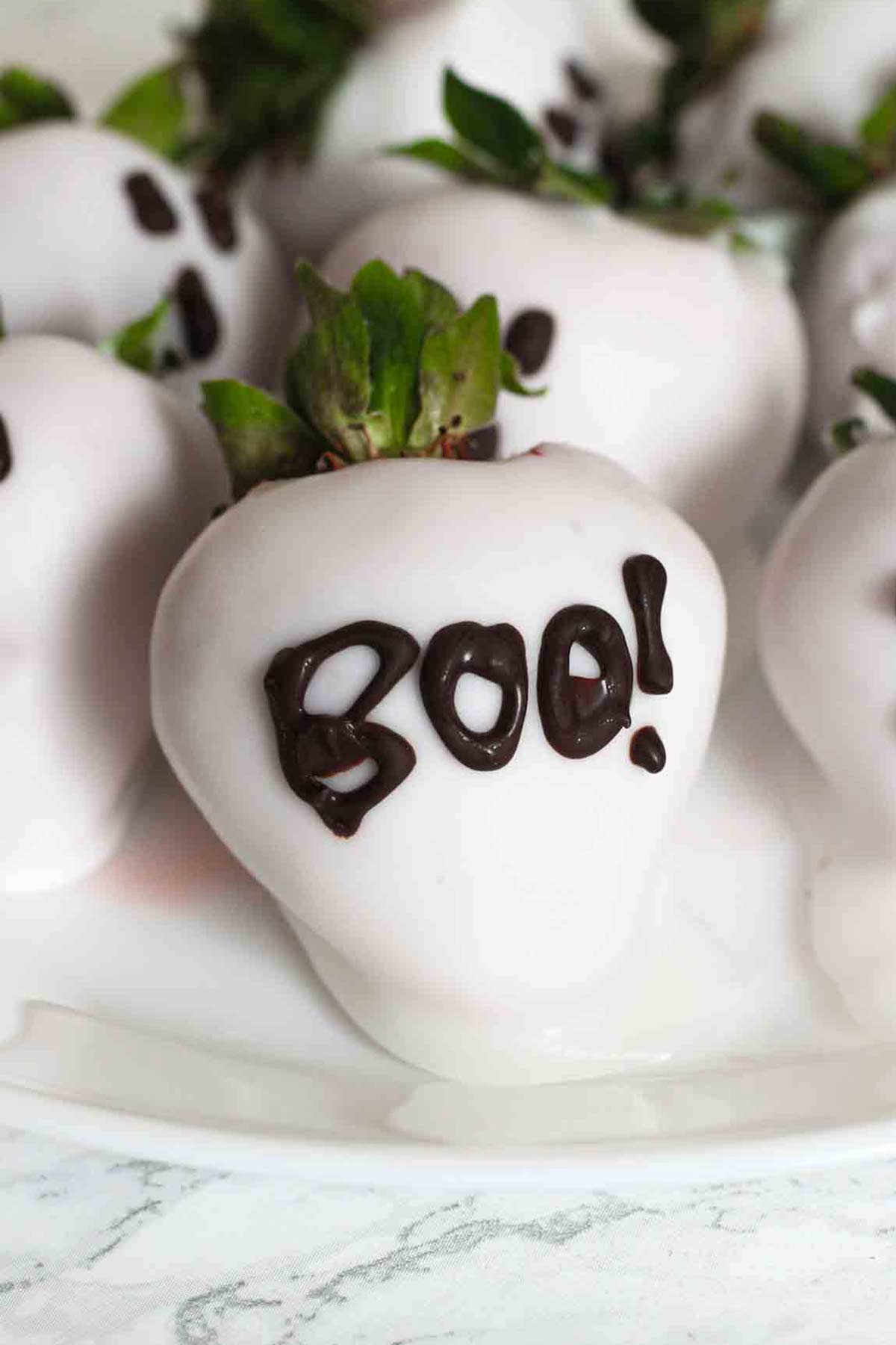 white halloween chocolate strawberries with boo written on the front one