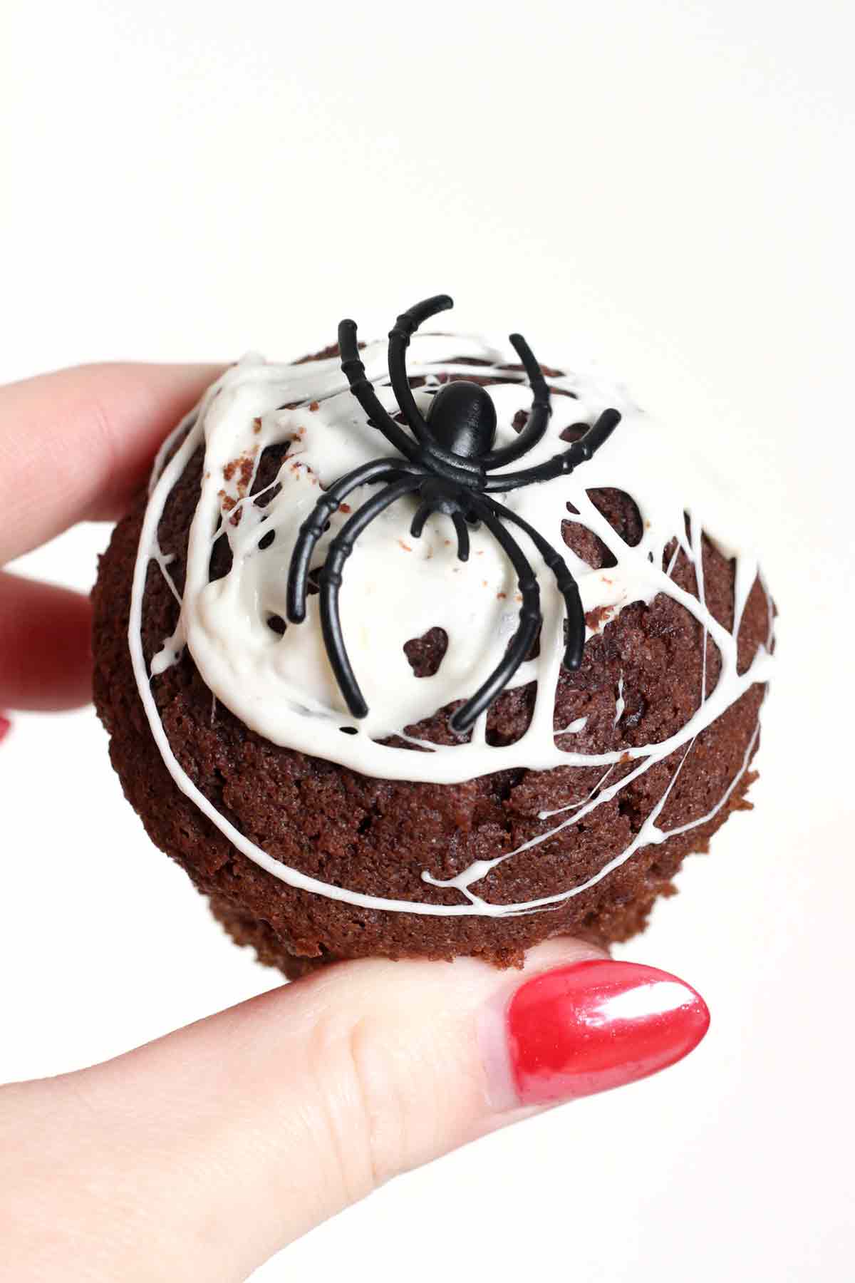 holding up halloween spider web muffin with marshmallow web on top