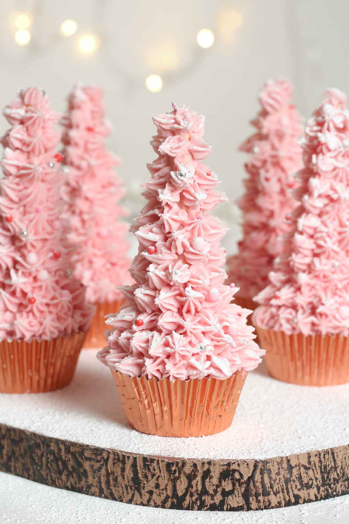 5 pink christmas tree cupcakes on a board