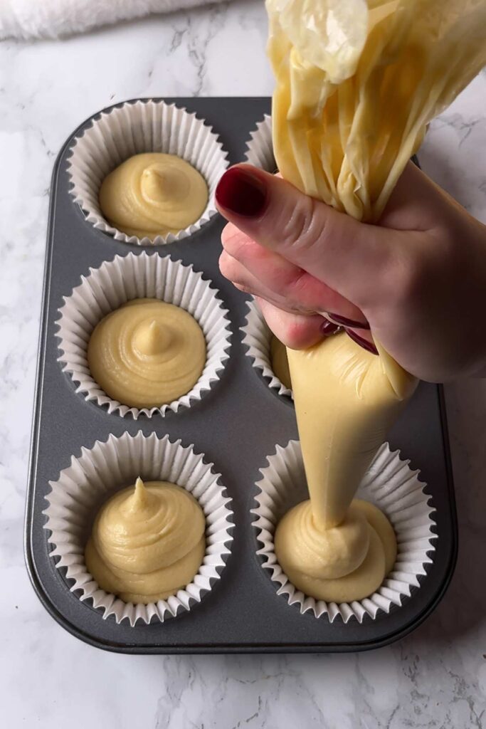 piping cake batter into cases