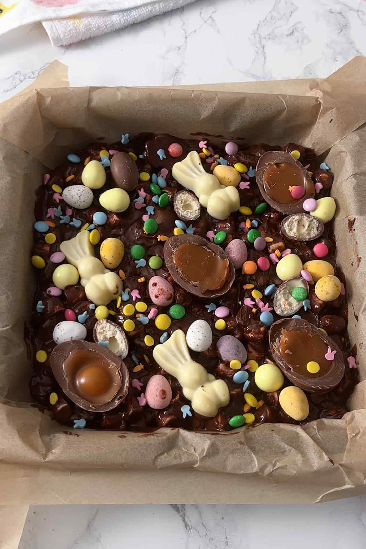 slab of rocky road in tin with various easter treats on top