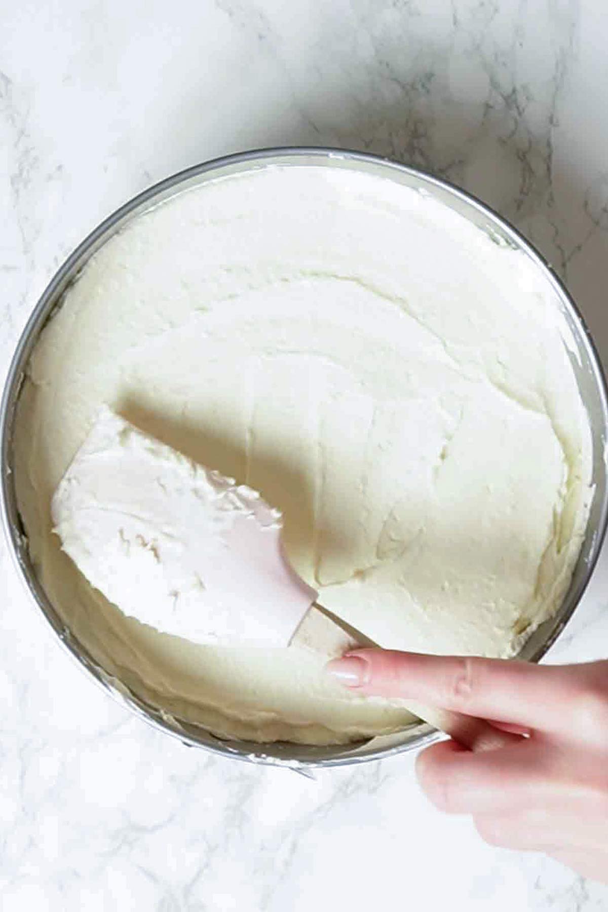 spreading cheesecake filling into tin 