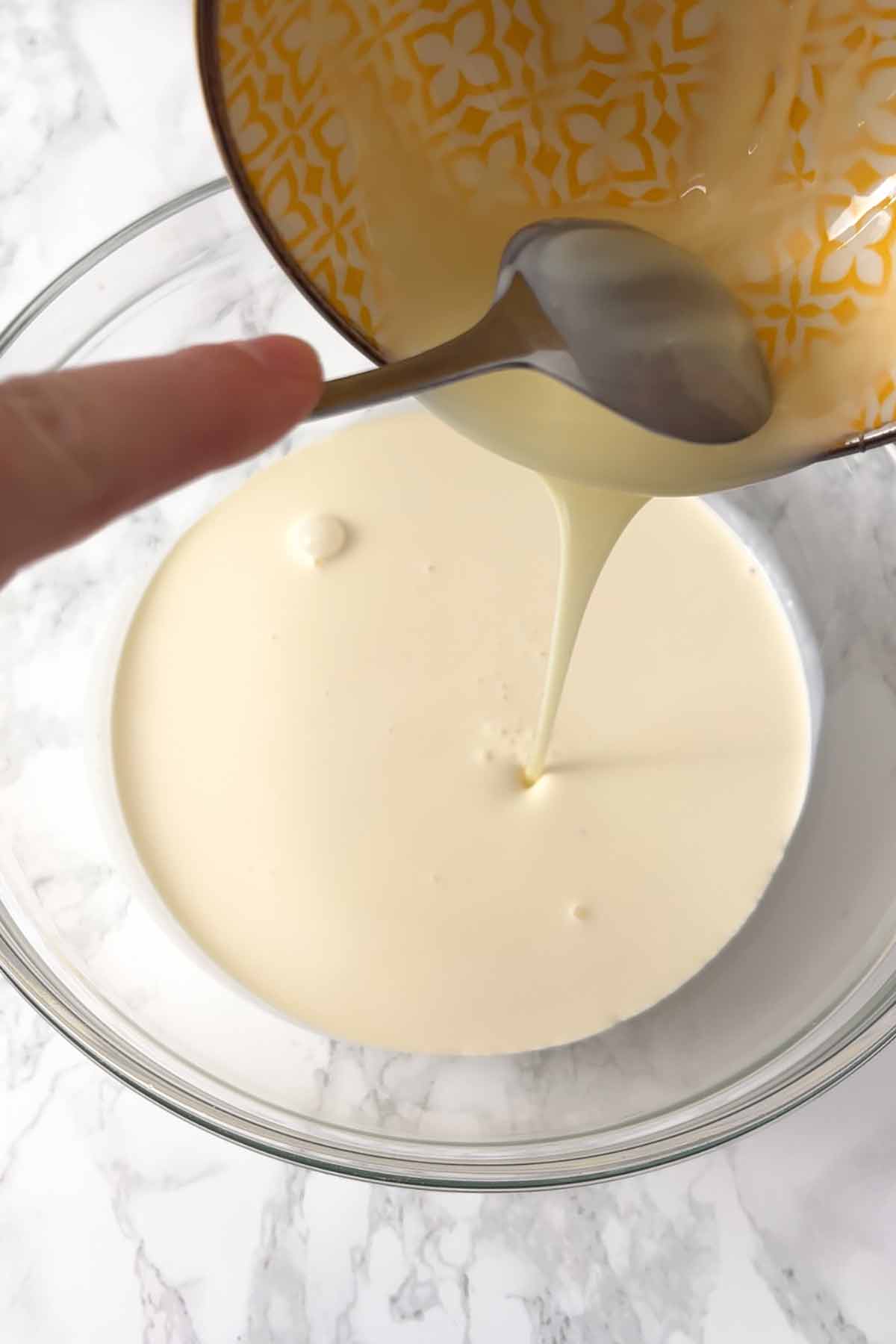 pouring condensed milk into bowl with double cream