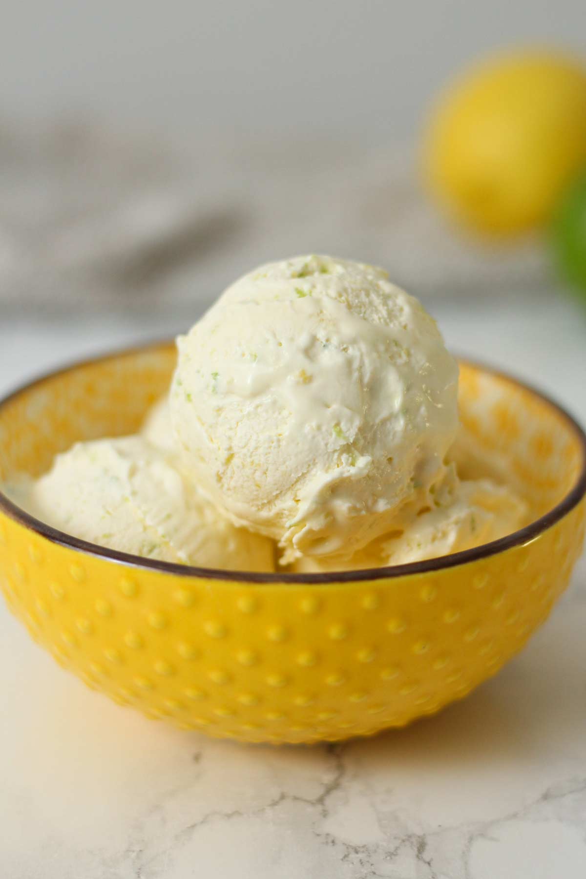 scoops of condensed milk lemon and lime ice cream in a yellow bowl