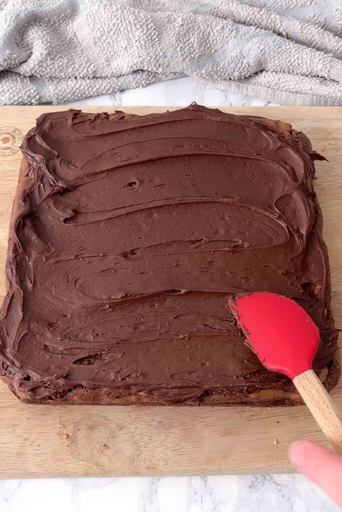 spreading chocolate frosting on top