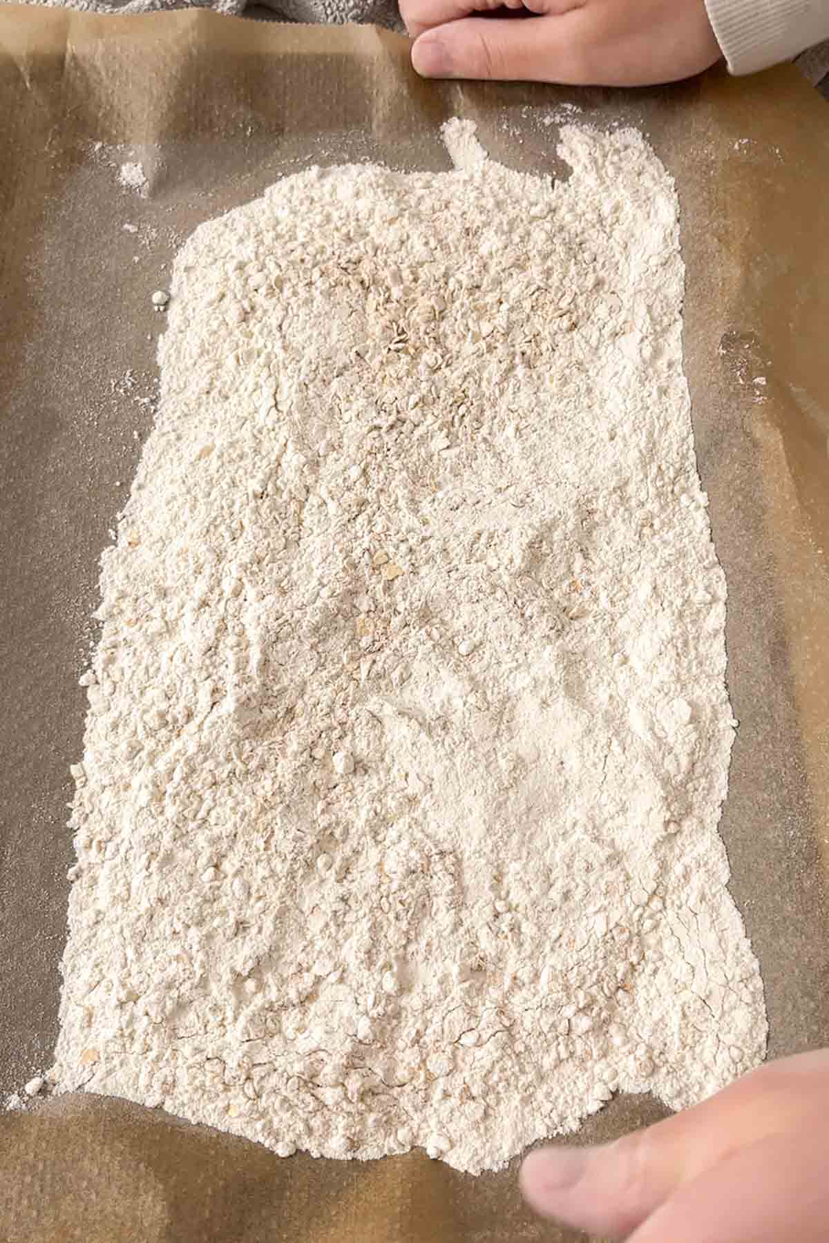 flour and oats spread out on a lined baking tray