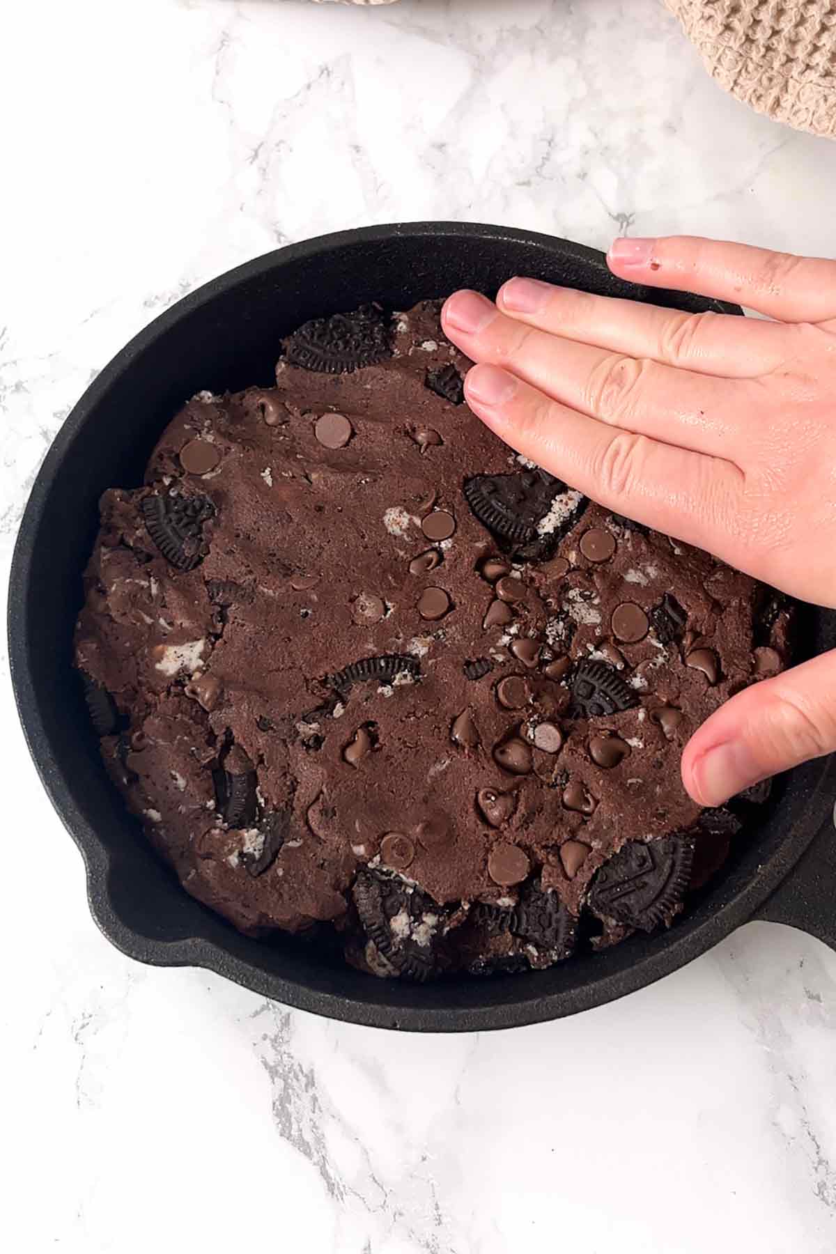 pressing the cookie dough into cast iron skillet
