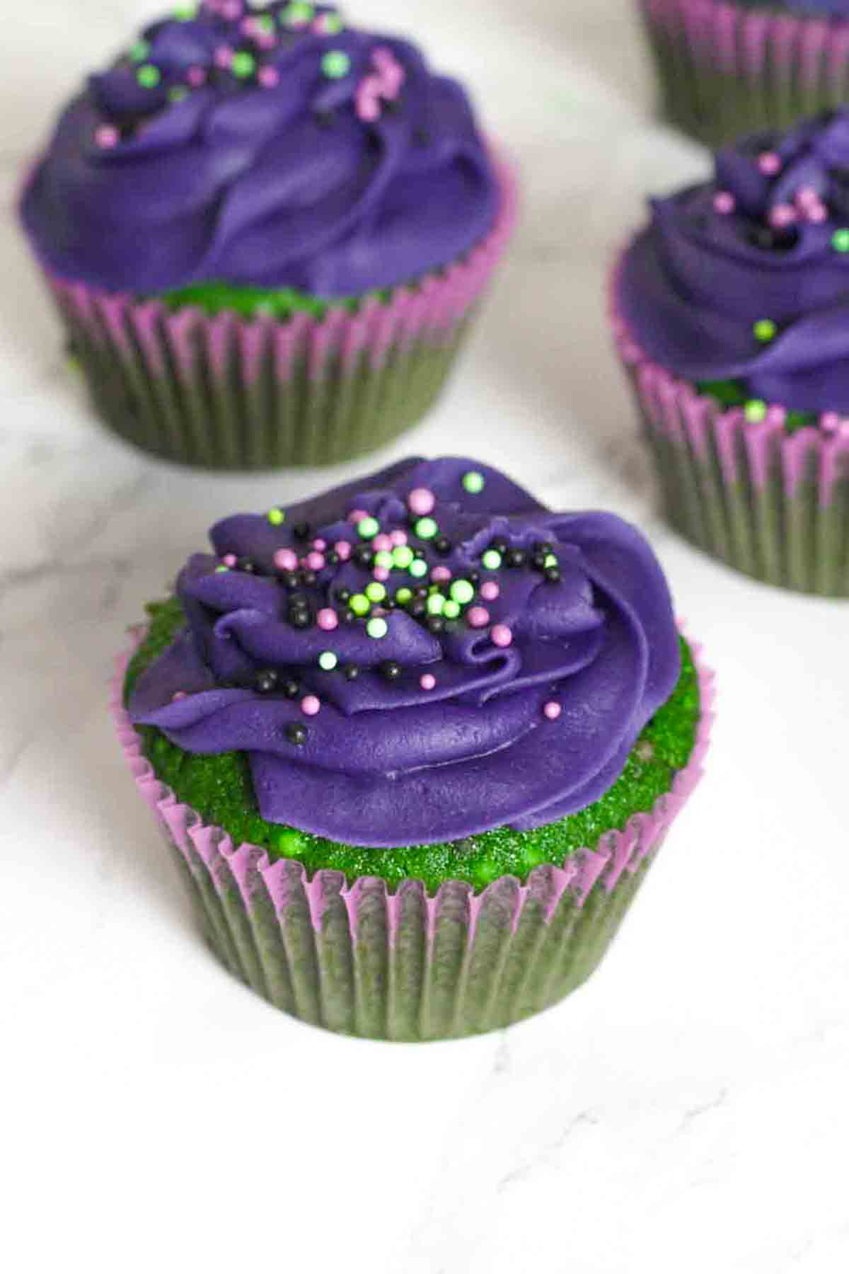 purple and green halloween funfetti cupcakes on a white surface