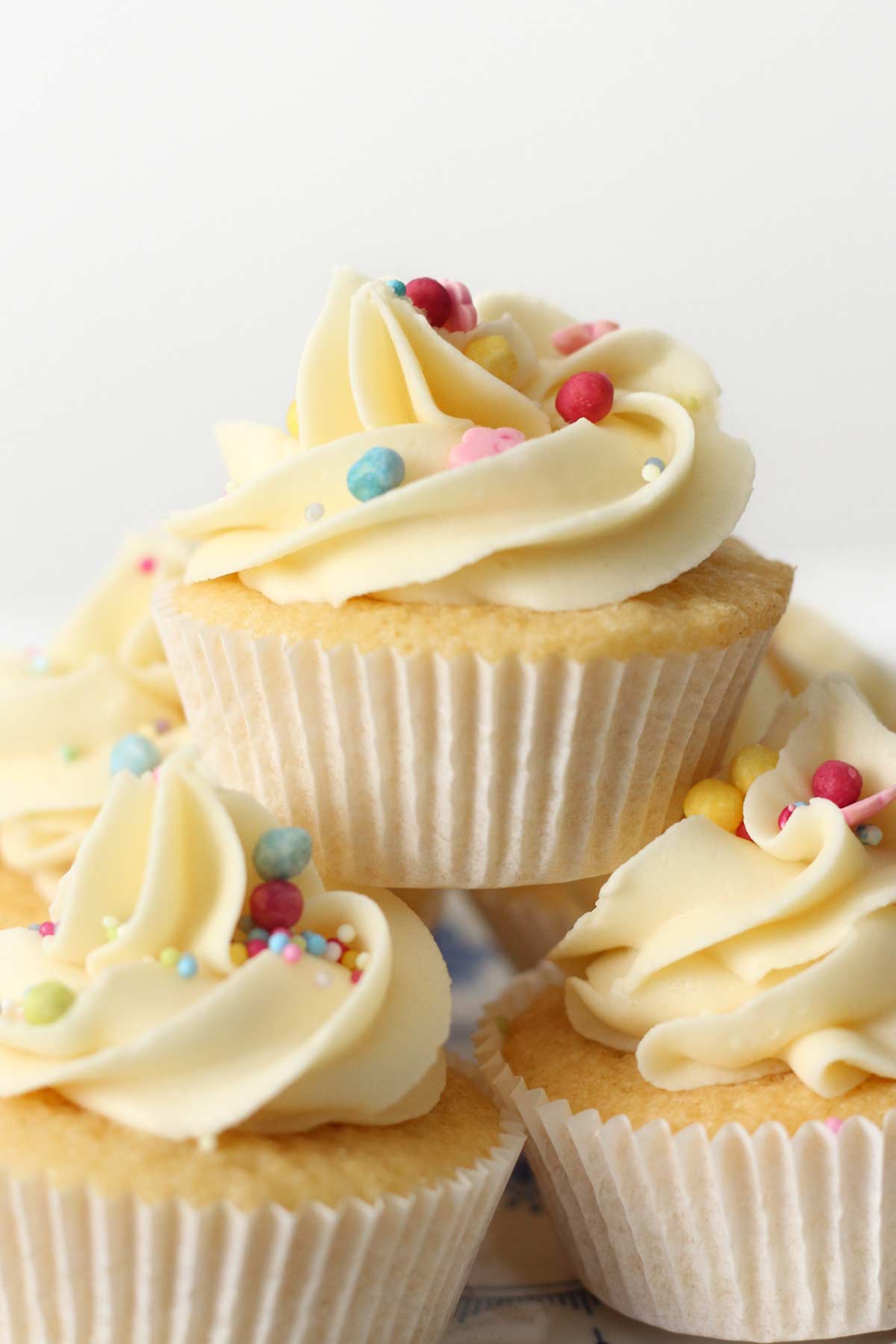 stack of mini fairy cakes with buttercream icing and sprinkles on top