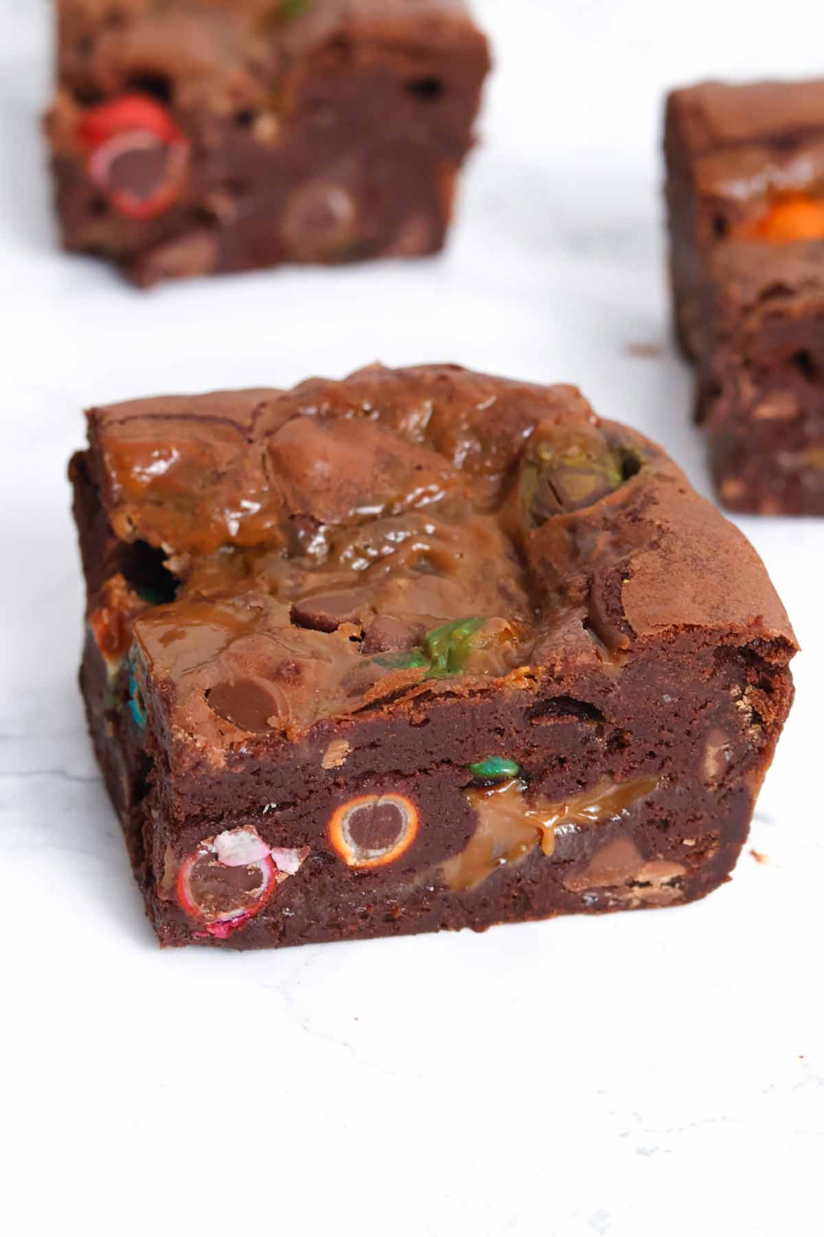 squares of caramel M&M brownies on a white surface