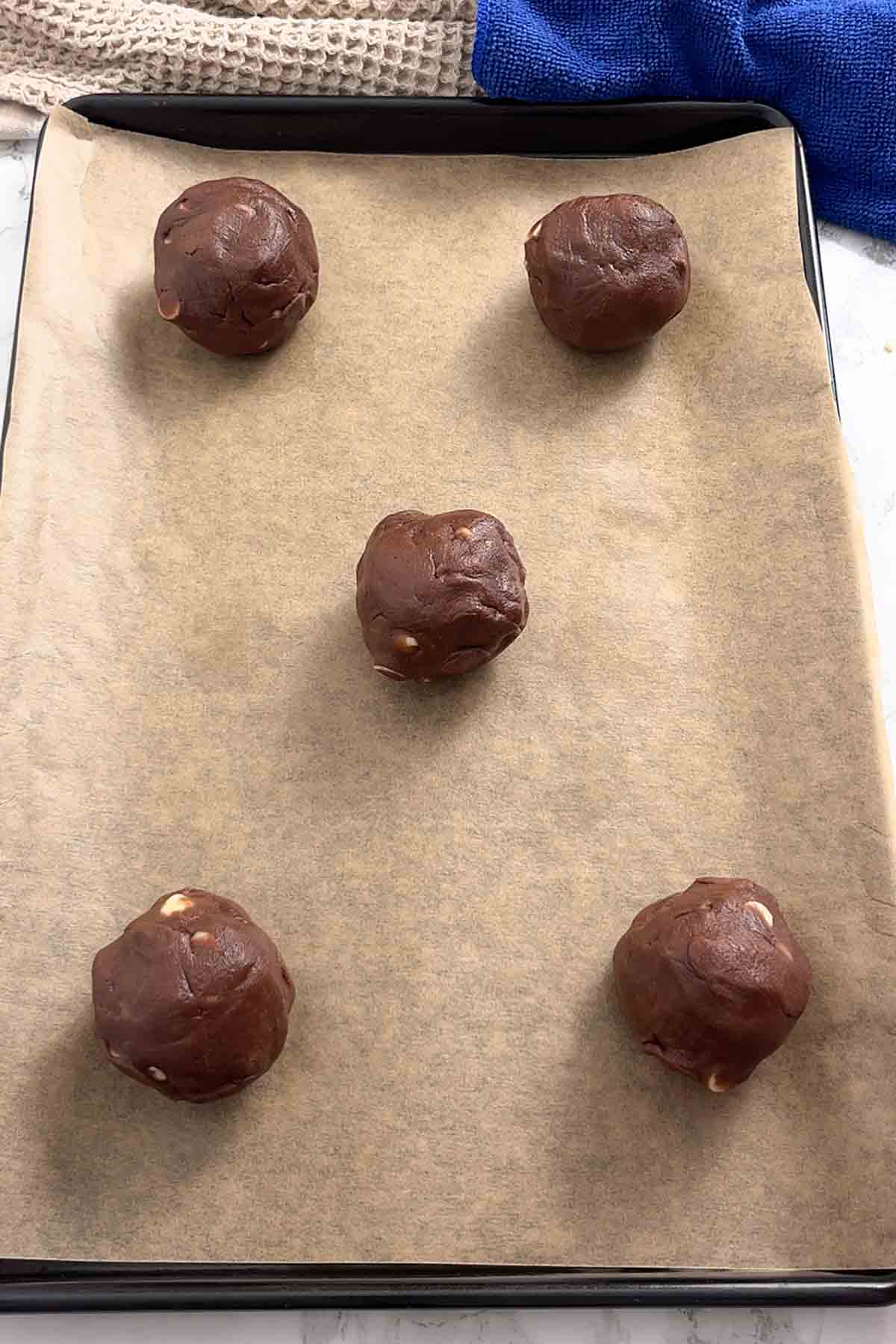 5 balls of dough on lined tray