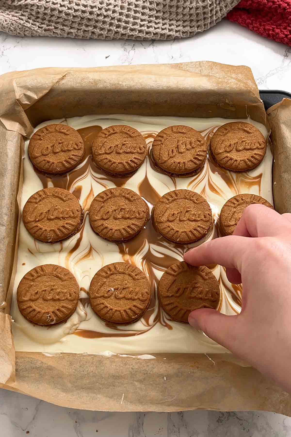placing biscoff biscuits on top of the melted topping