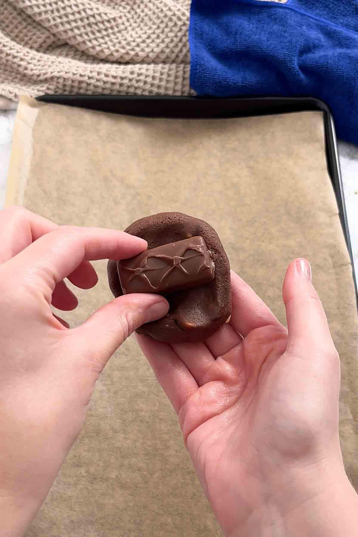 placing milky way bar into the cookie dough