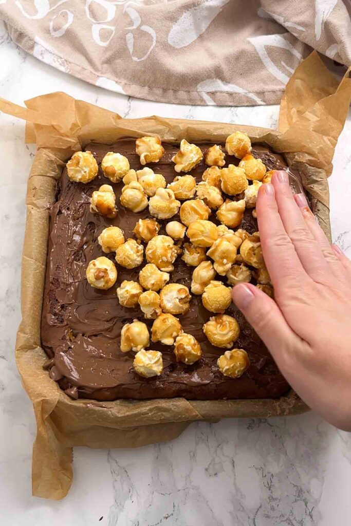 pressing popcorn on top of the melted chocolate