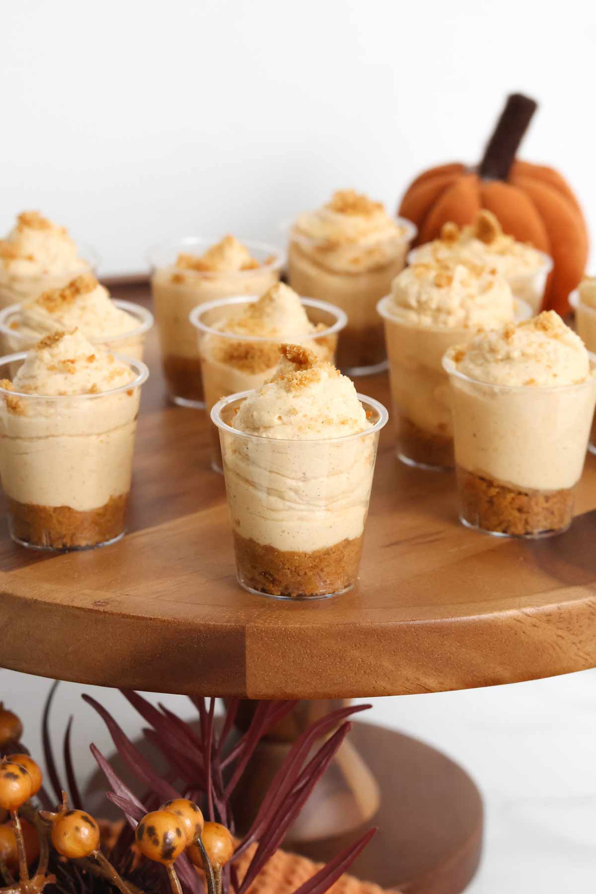 pumpkin cheesecake shooters on a brown cake stand