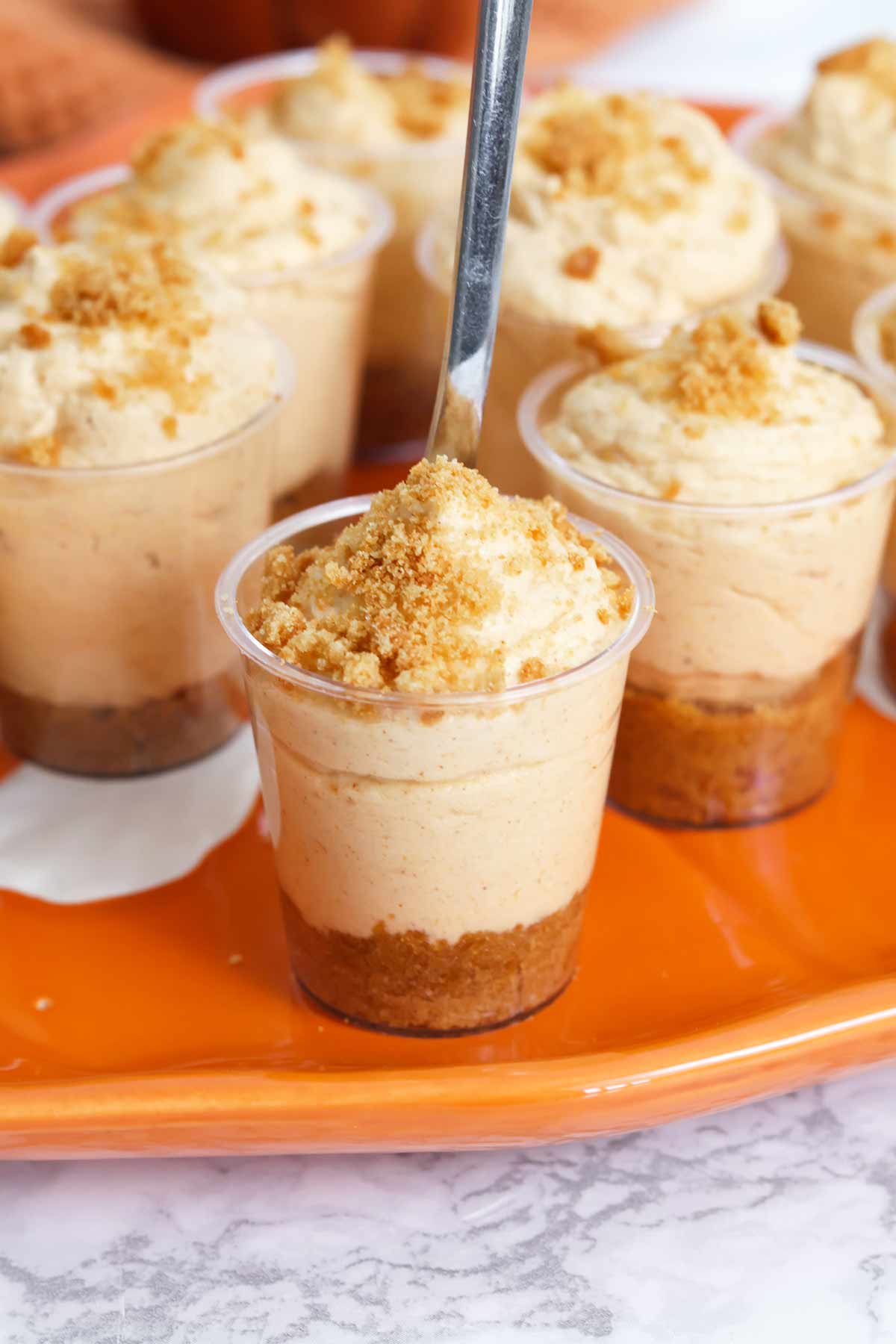 pumpkin spice cheesecake shooters on an orange