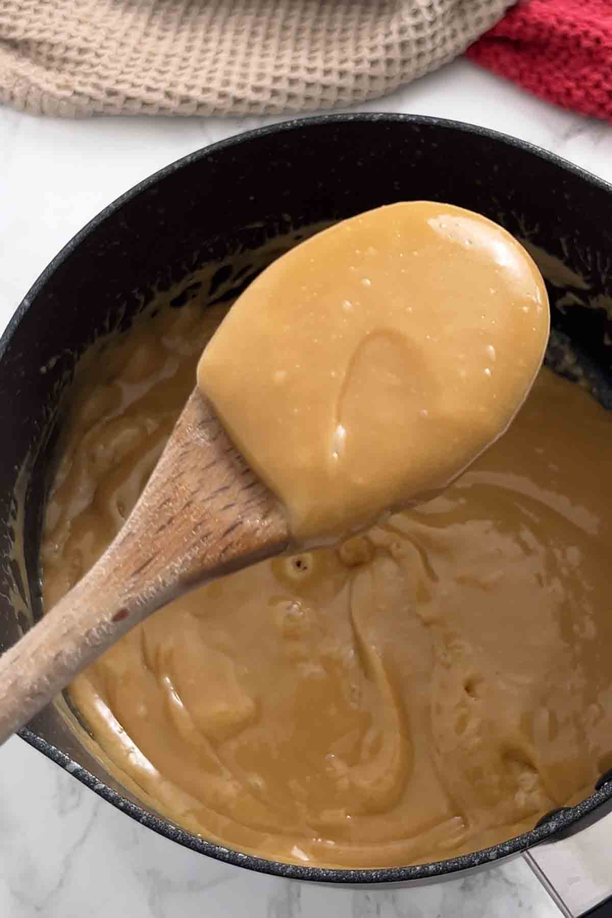 thickened caramel on a wooden spoon