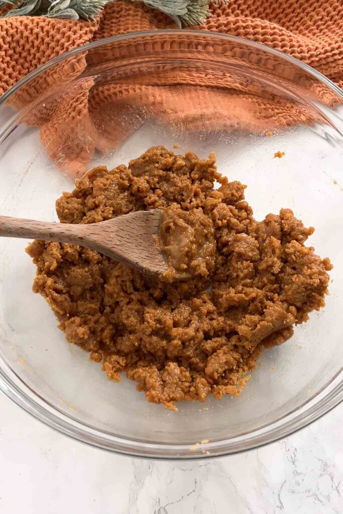 bowl of gingernut biscuit crumbs in a bowl covered with butter and condensed milk