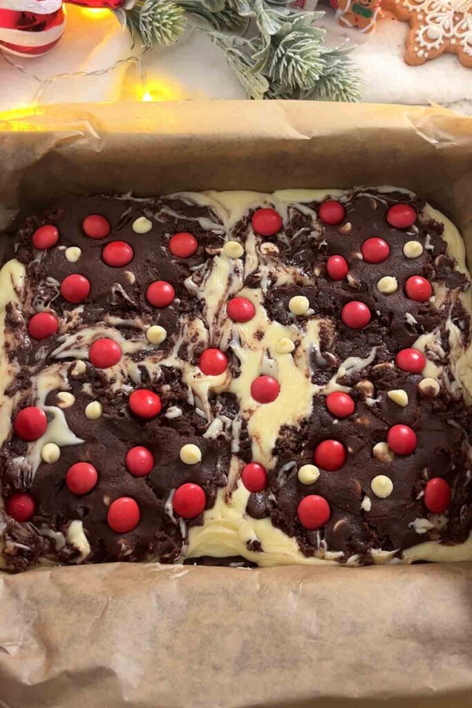 cookie dough in tin with fudge, red m and ms and white chocolate chips on top