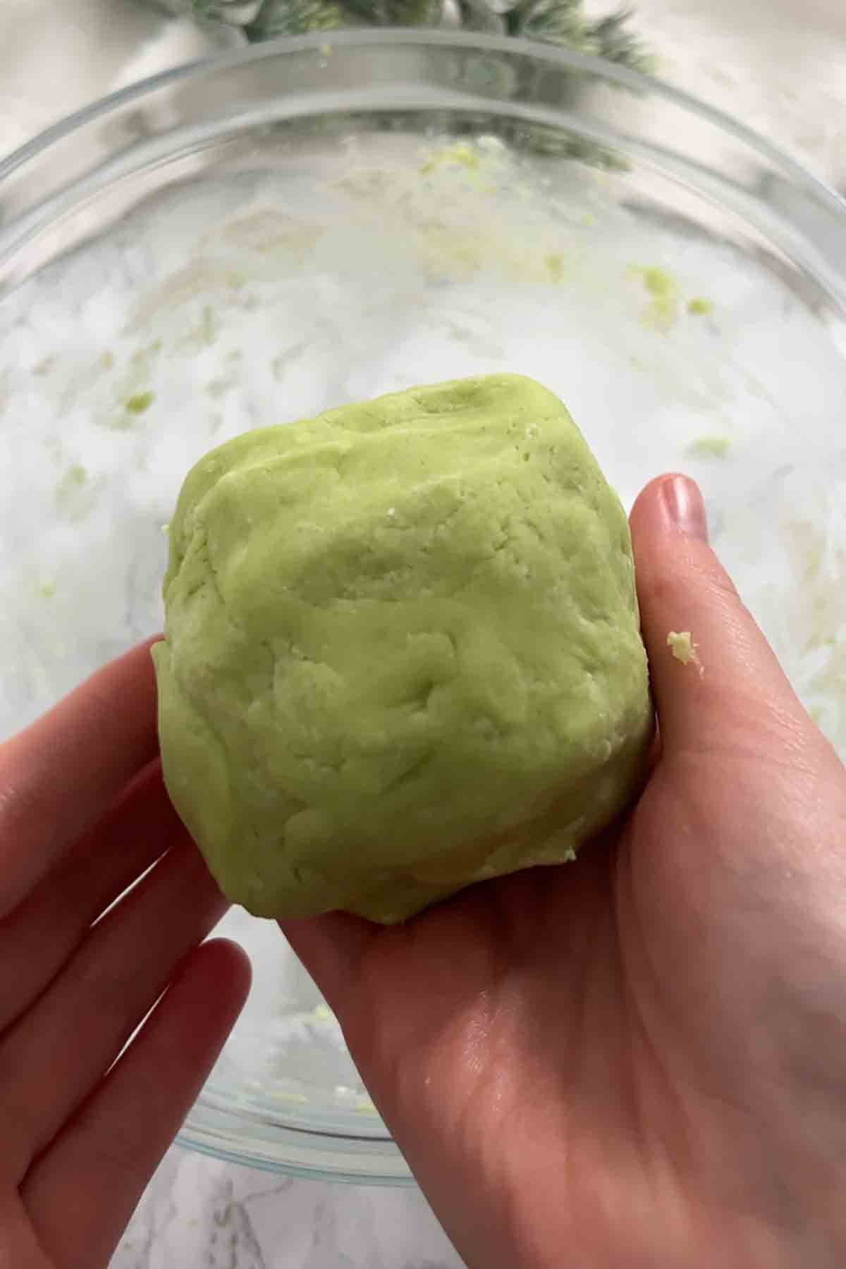 hands holding a ball of light green dough