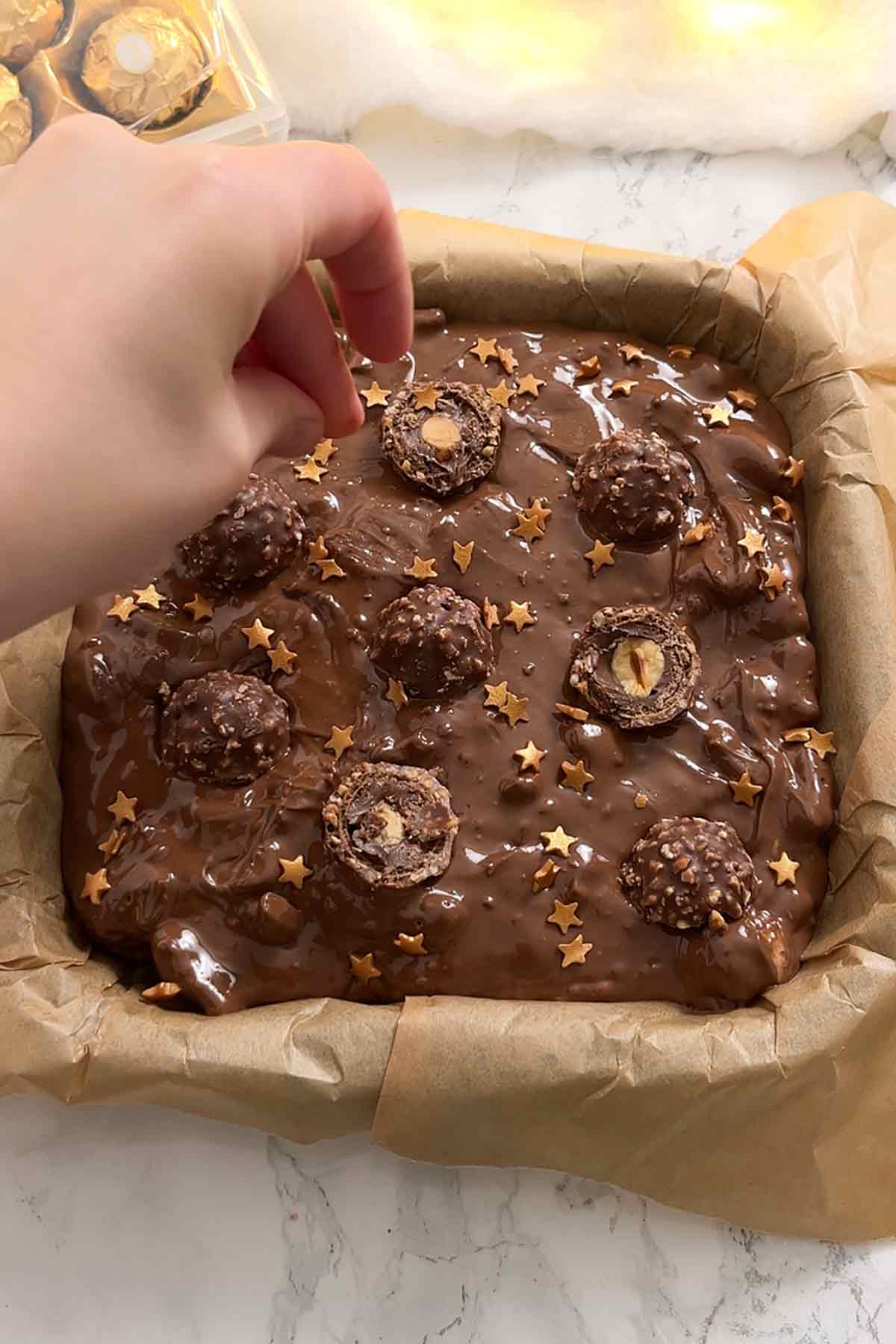 placing star sprinkles on top of the tiffin in the tin