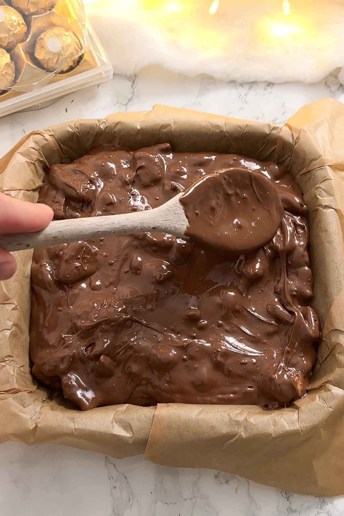 pressing the tiffin mixture into a lined tin
