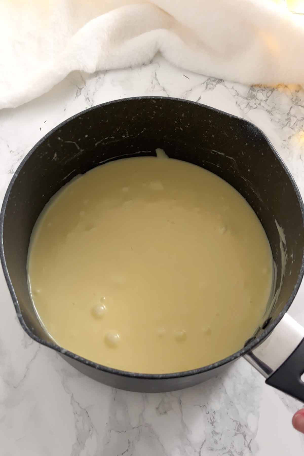 condensed milk and white chocolate melted together in a saucepan