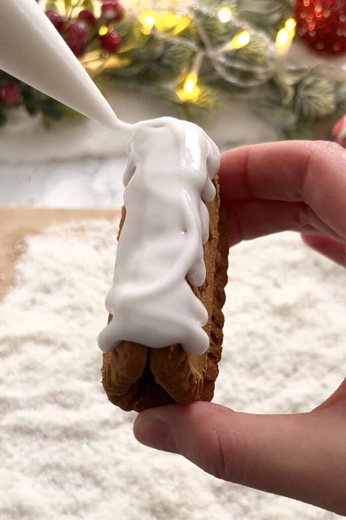 piping icing onto the biscuit roof