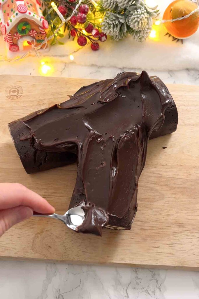 spreading chocolate ganache onto the log