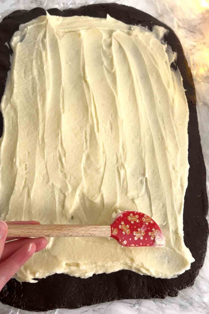spreading the vanilla buttercream onto the biscuit sheet
