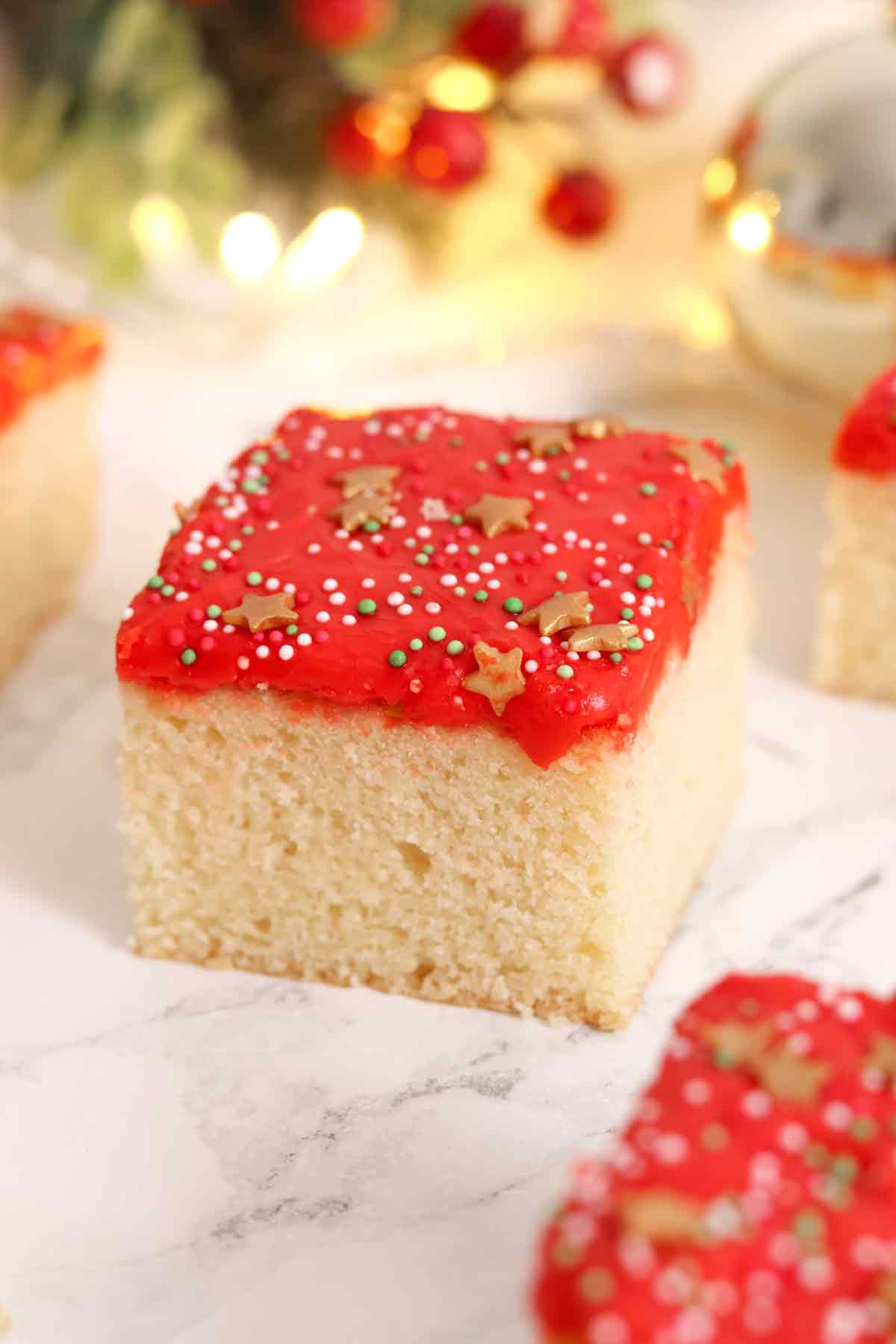 squares of christmas sponge traybake cake with festive decor in the background