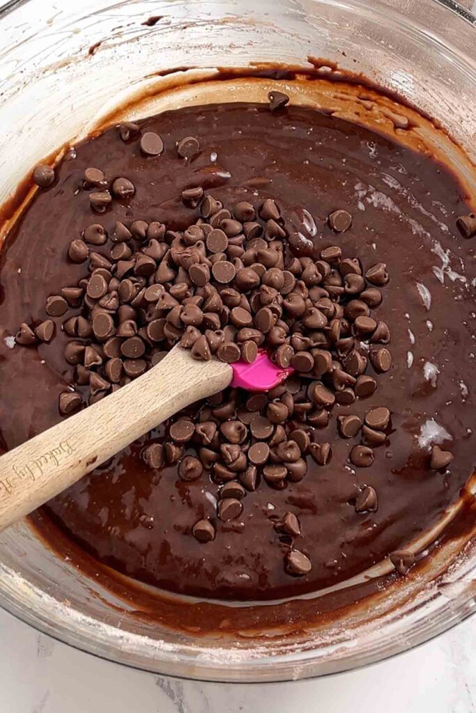 brownie mixture in a glass bowl with a pink spatula