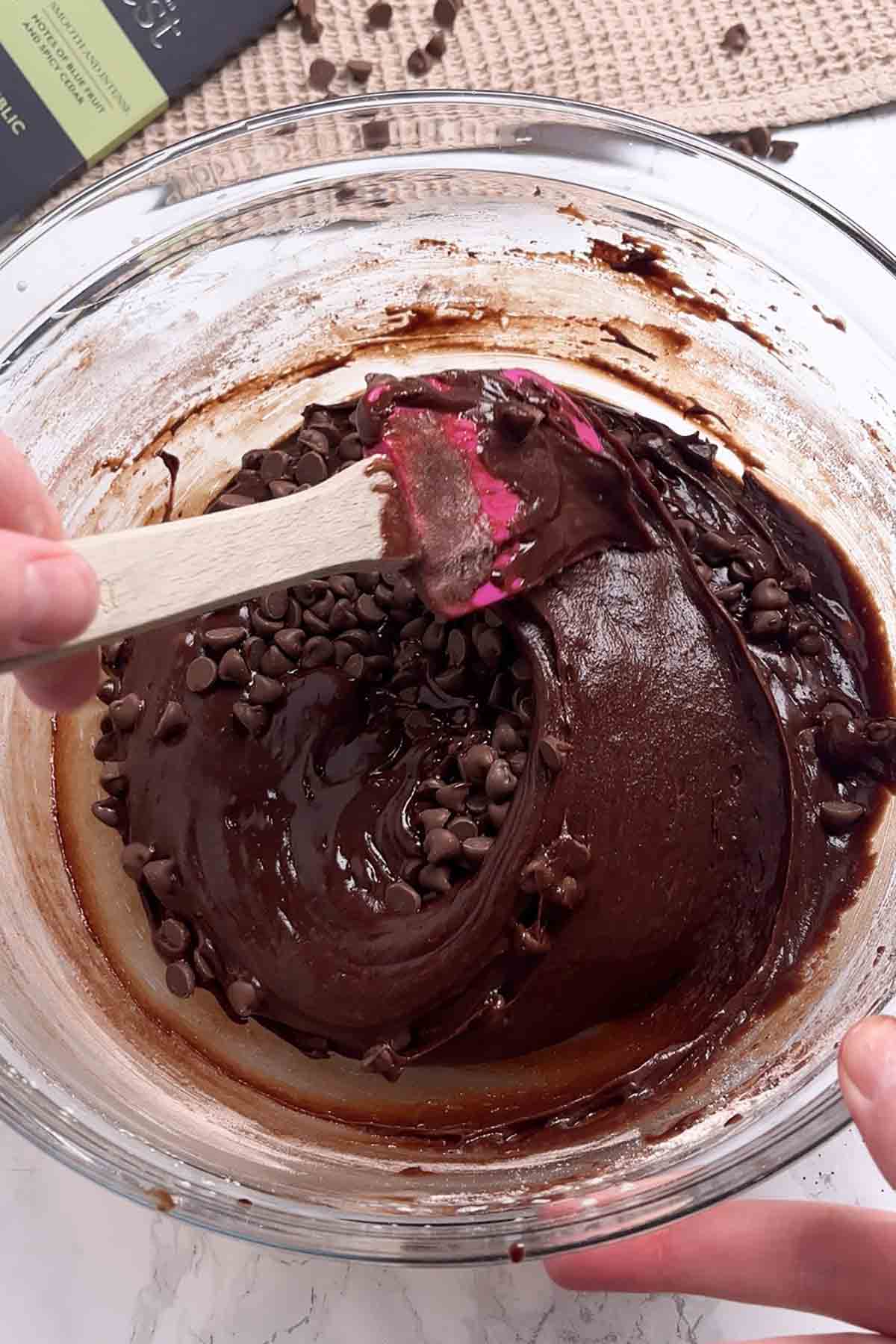 brownie batter and milk chocolate chips being mixed together in a bowl