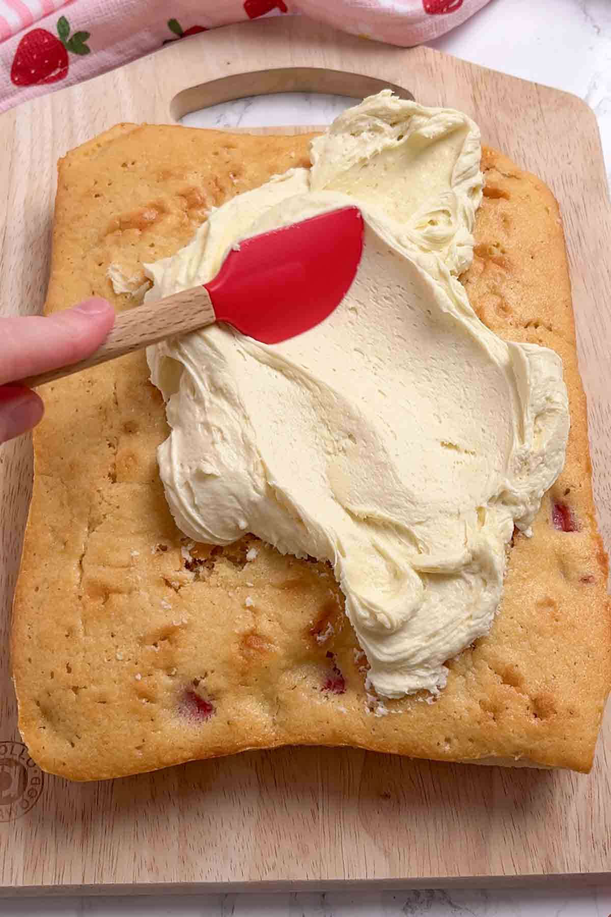spreading white chocolate ganache onto the cake