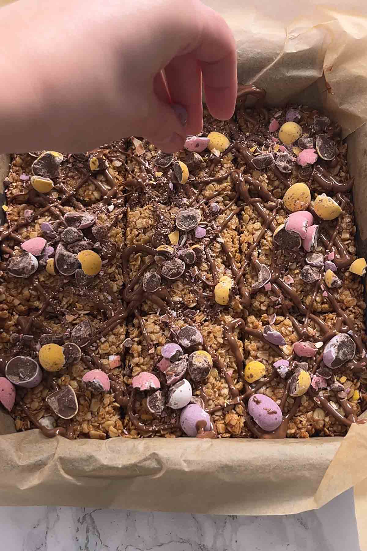 sprinkling crushed chocolate eggs onto the flapjacks