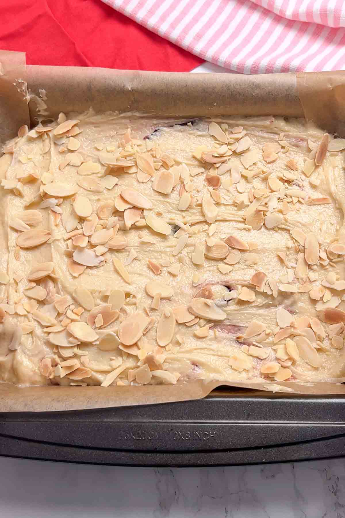 cake batter with flaked almonds on top in a lined tin