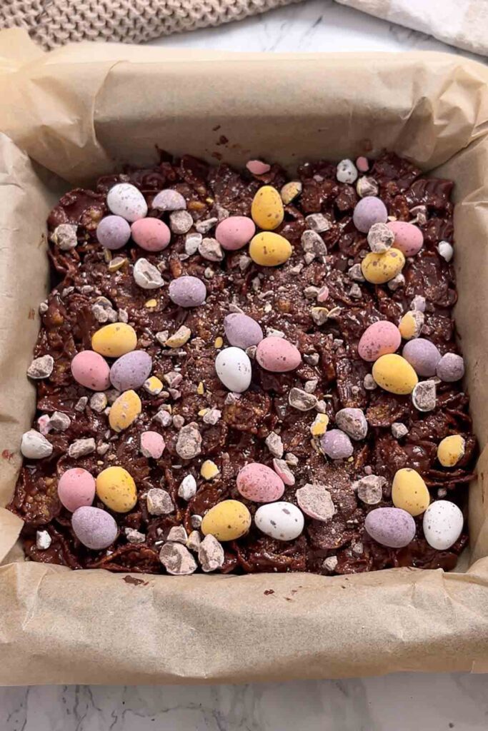 chocolate cornflake mixture packed into a lined tin with mini eggs on top