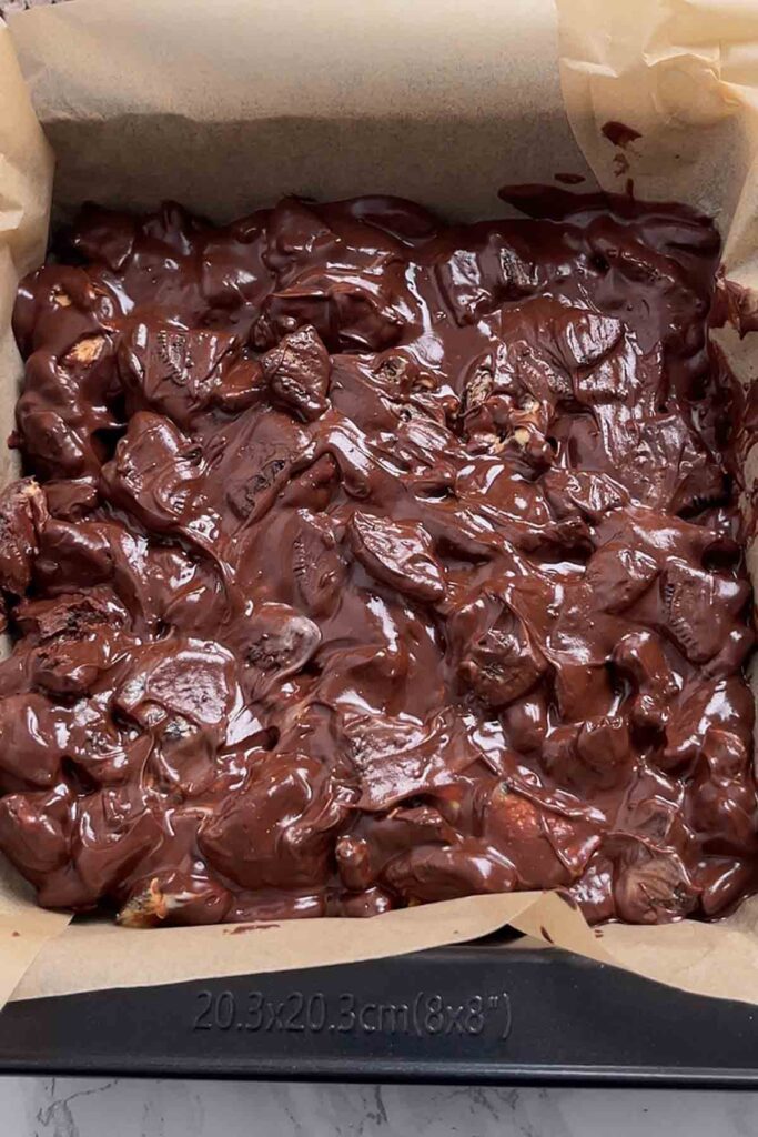 creme egg tiffin mixture pressed in lined tin