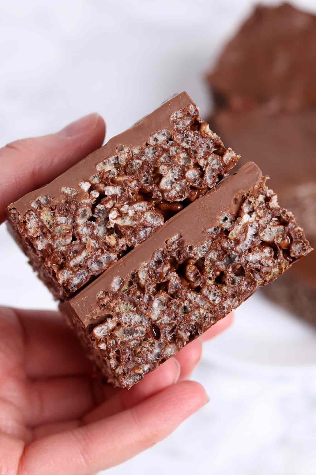 hand holding up 2 chocolate marshmallow rice krispie traybake bars
