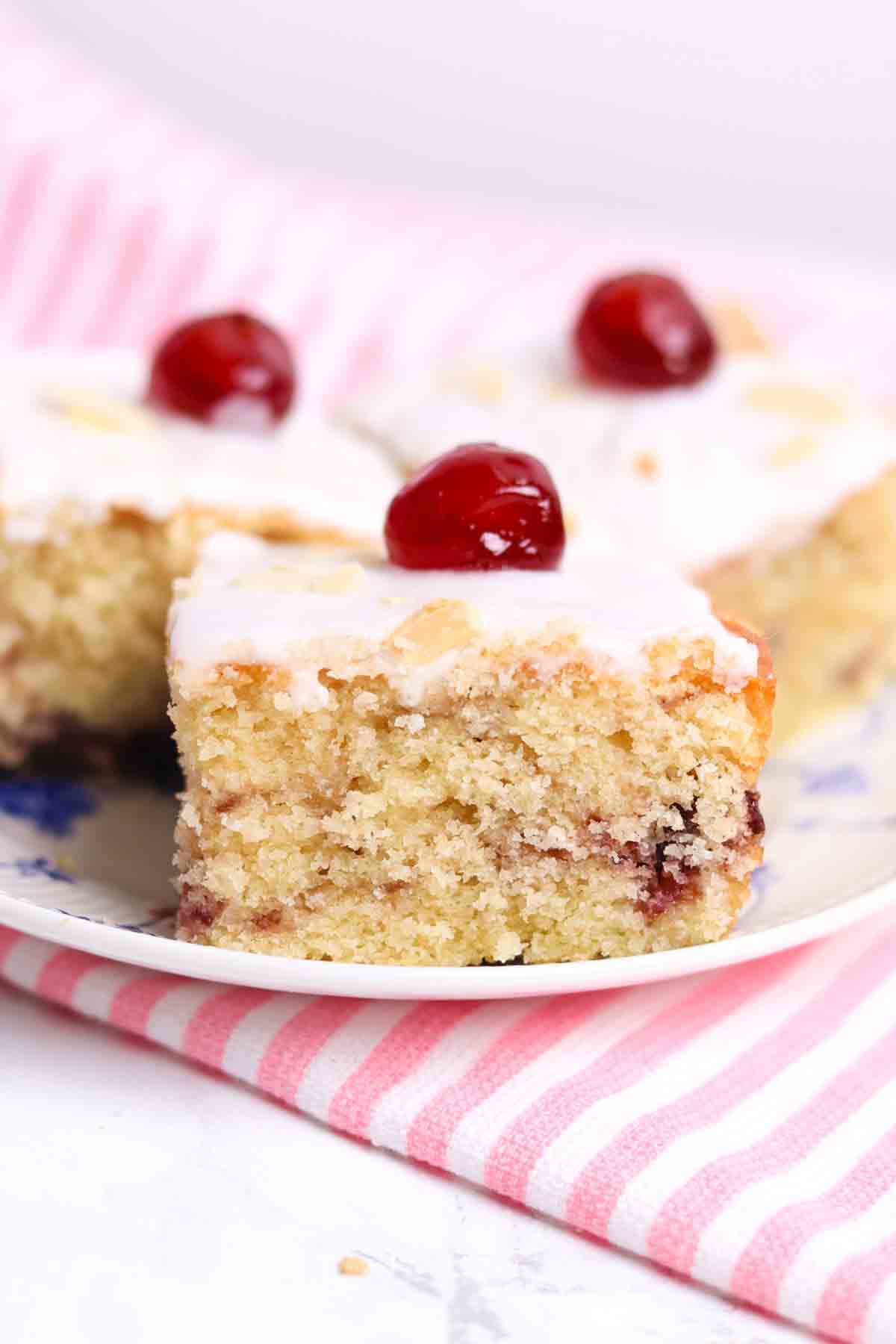 image of 3 slices of cherry bakewell traybake without pastry on a white and blue plate